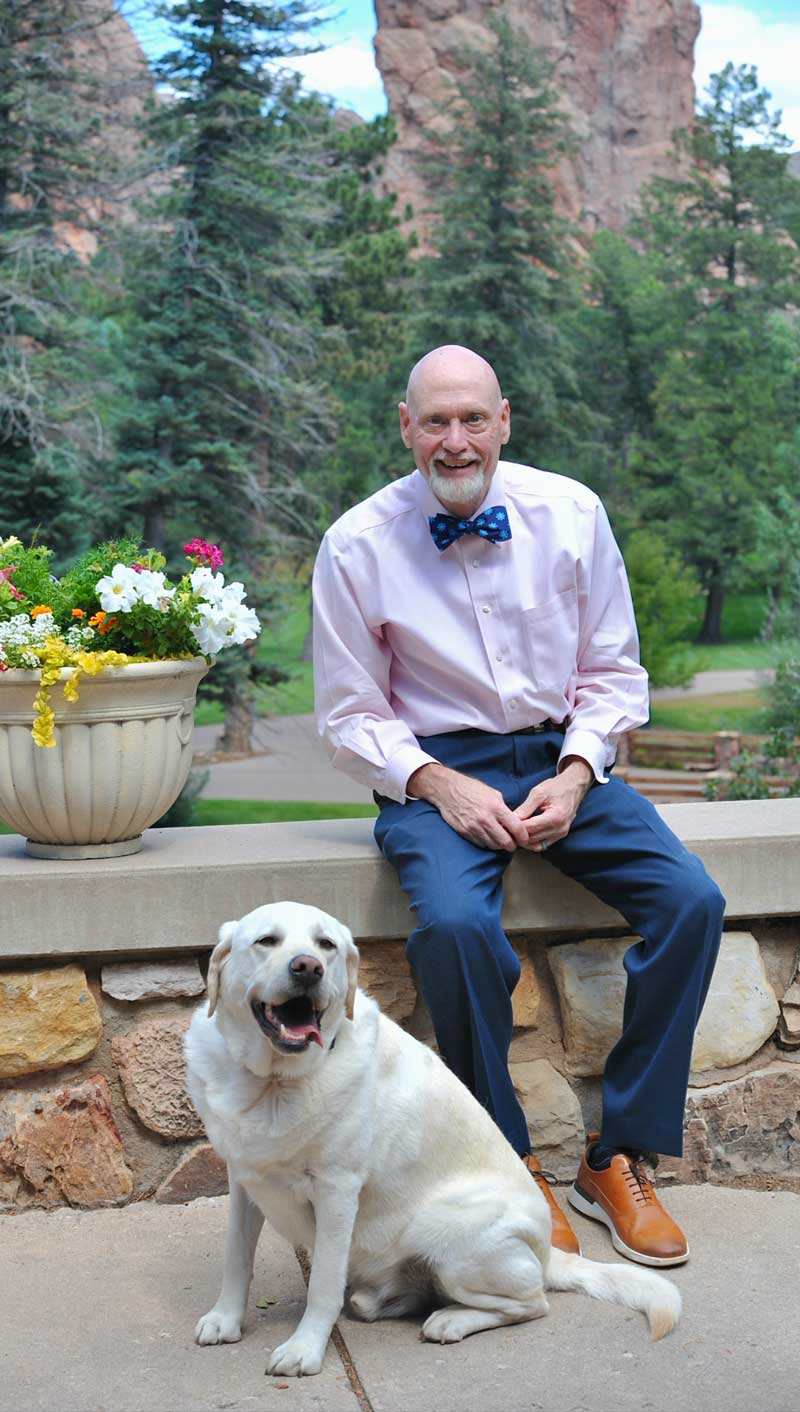Bob Barrows with his dog, Norman, sitting outside at the Glen Eyrie castle
