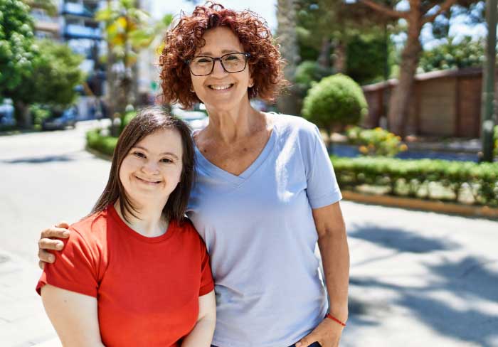 Mature mother and down syndrome daughter smiling happy and friendly outdoors